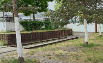 Das Bild zeigt die noch existierenden Gleise des ehemaligen Güterbahnhofs. Die Gleise werden durch Bäume gerahmt.