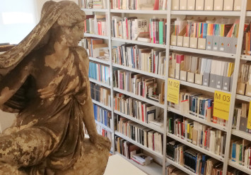 Statue vor Bücherregal 