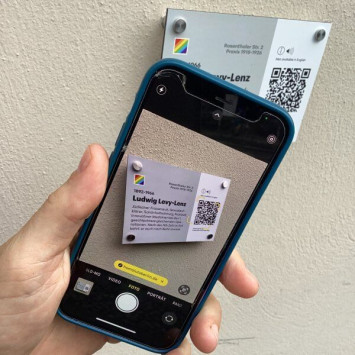 Mithilfe eines Handys wird der QR-Code gescannt, um zu den verknüpften Informationen zu kommen.